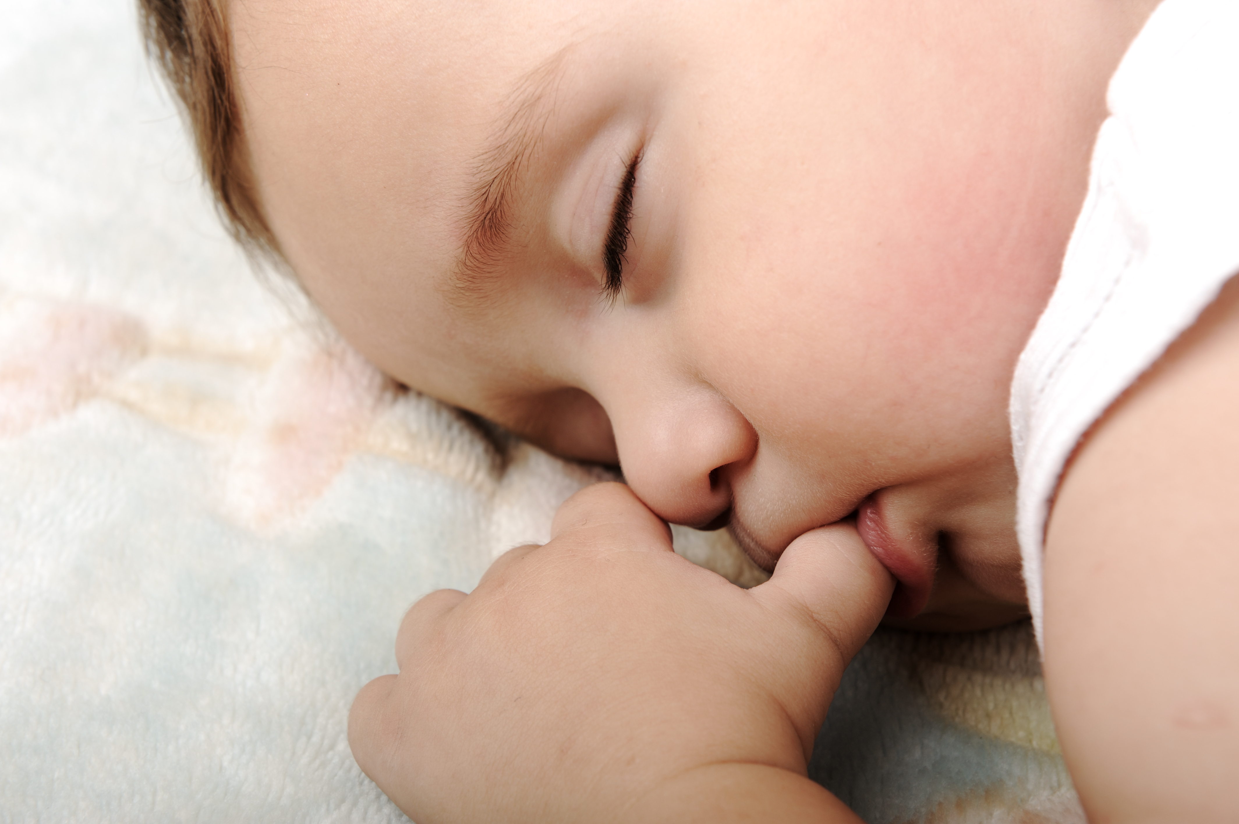 Грудное сосание. Спящий младенец. Сосательный рефлекс у младенца. Младенец с пальцем во рту. Сосание новорожденного.